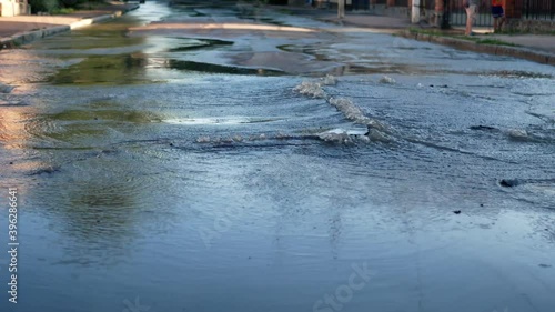 Break of the water pipe. Water beats out of the ground from the cracks in the asphalt road surface 