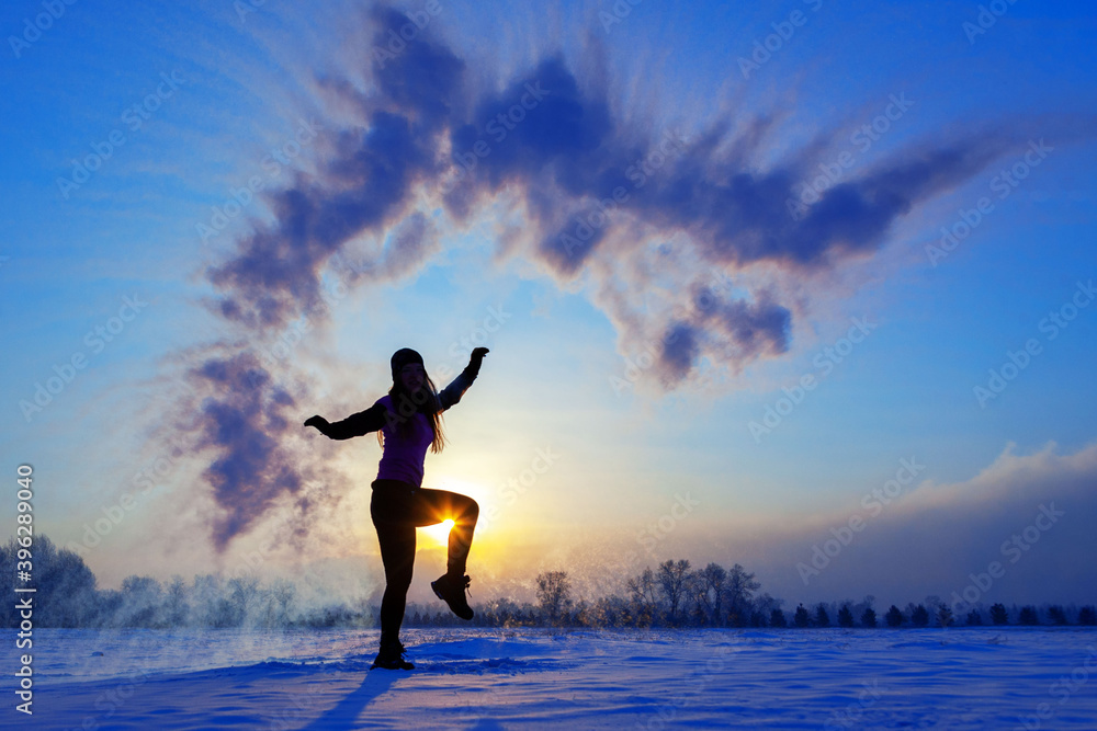 Silhouette of a sports girl at sunset in winter. Woman splashed boiling water on cold air. Silhouette of a sports girl at sunset in winter. Woman splashed boiling water on cold air.
