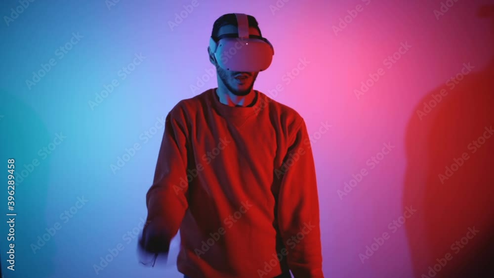 Male gamer playing virtual reality game slashing left and right using VR controllers in both hands Male gamer playing virtual reality game slashing left and right using VR controllers in both hands