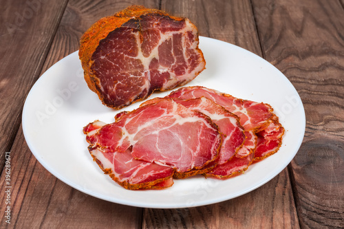 Partly sliced dried pork neck on dish, selective focus