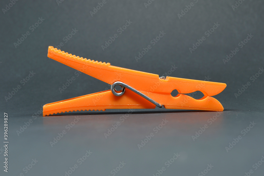 tweezers spreading orange clothes on gray background