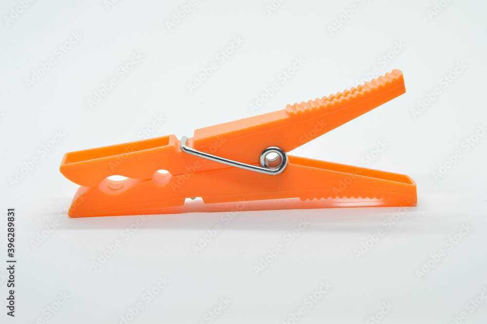 tweezers spreading orange clothes on white background tweezers spreading orange clothes on white background