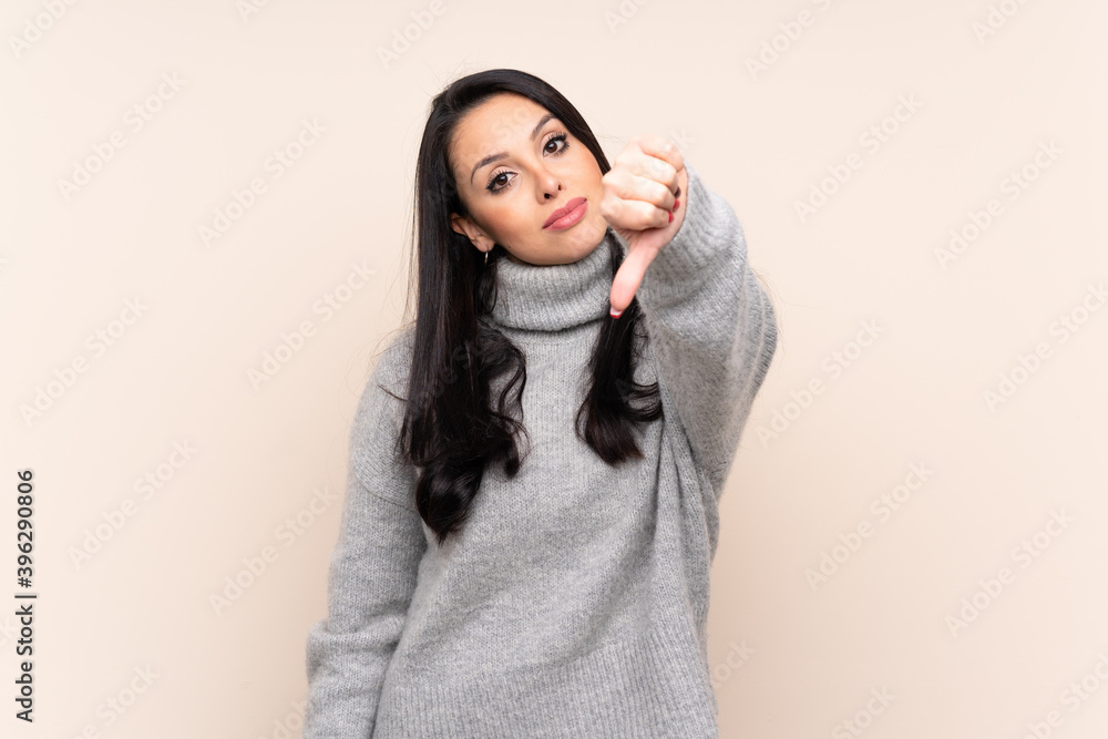 Young Colombian girl over isolated background showing thumb down with negative expression Young Colombian girl over isolated background showing thumb down with negative expression