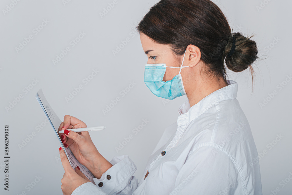 a masked nurse fills out papers during a covid-19 pandemic a masked nurse fills out papers during a covid-19 pandemic
