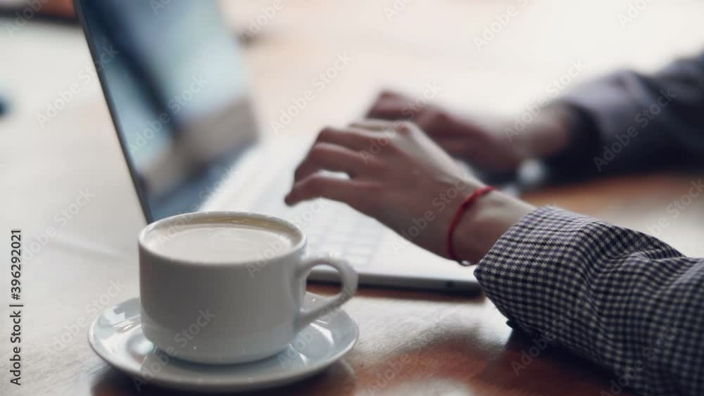Freelancer works at a laptop while sitting in a cafe Freelancer works at a laptop while sitting in a cafe