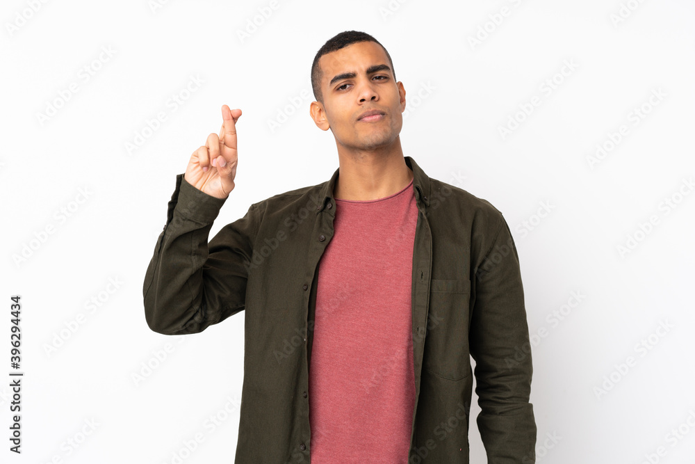 Young African American man over isolated white background with fingers crossing and wishing the best Young African American man over isolated white background with fingers crossing and wishing the best