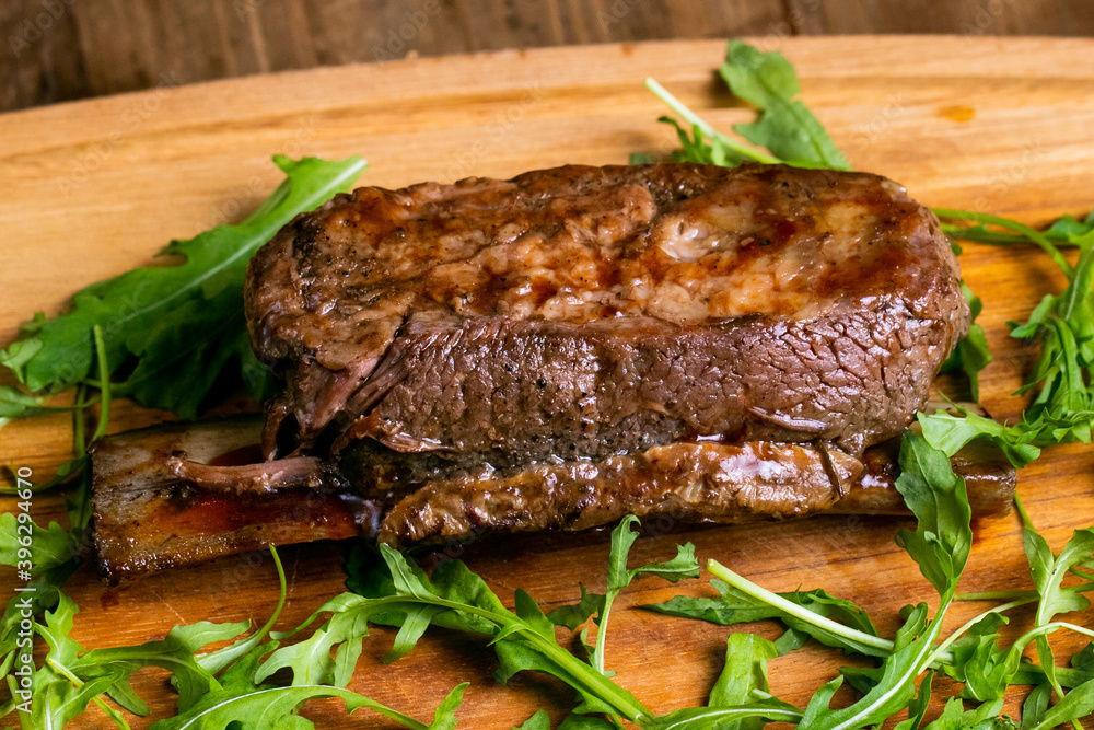 Delicious grilled short beef ribs with green isolated on a wooden(bamboo) tray close up. Delicious grilled short beef ribs with green isolated on a wooden(bamboo) tray close up.