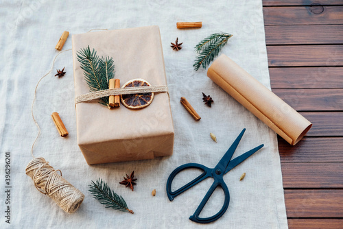 Fototapeta Naklejka Na Ścianę i Meble -  Wrapping gifts with natual decorations such as fir branch, cinnamon sticks, dry orange slice. Zero waste Christmas concept. Plastic free holidays. Sustainable lifestyle.