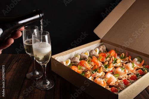Champagne, tartlets, seafood salads. Cardboard box with food with home delivery. Gift for holiday, party, family dinner. Catering. Delicious snacks.