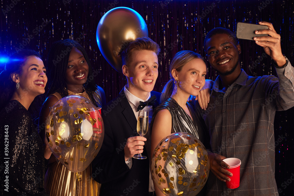 Waist up portrait of multi-ethnic group of friends taking selfie with baloons while enjoying Birthday party or prom night - obrazy, fototapety, plakaty 