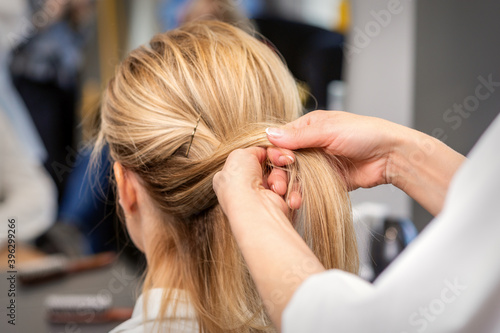 Close up of the hairdresser's hands braiding the client's hair in a beauty salon