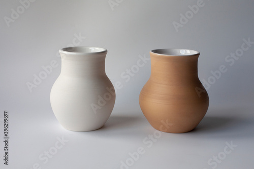 Two ceramic milk pots of white and terracotta clay. Rustic style. Fotobehang