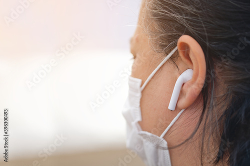 Woman wearing protective face mask and phone headset in Covid-19 corona virus epidemic disease. photo