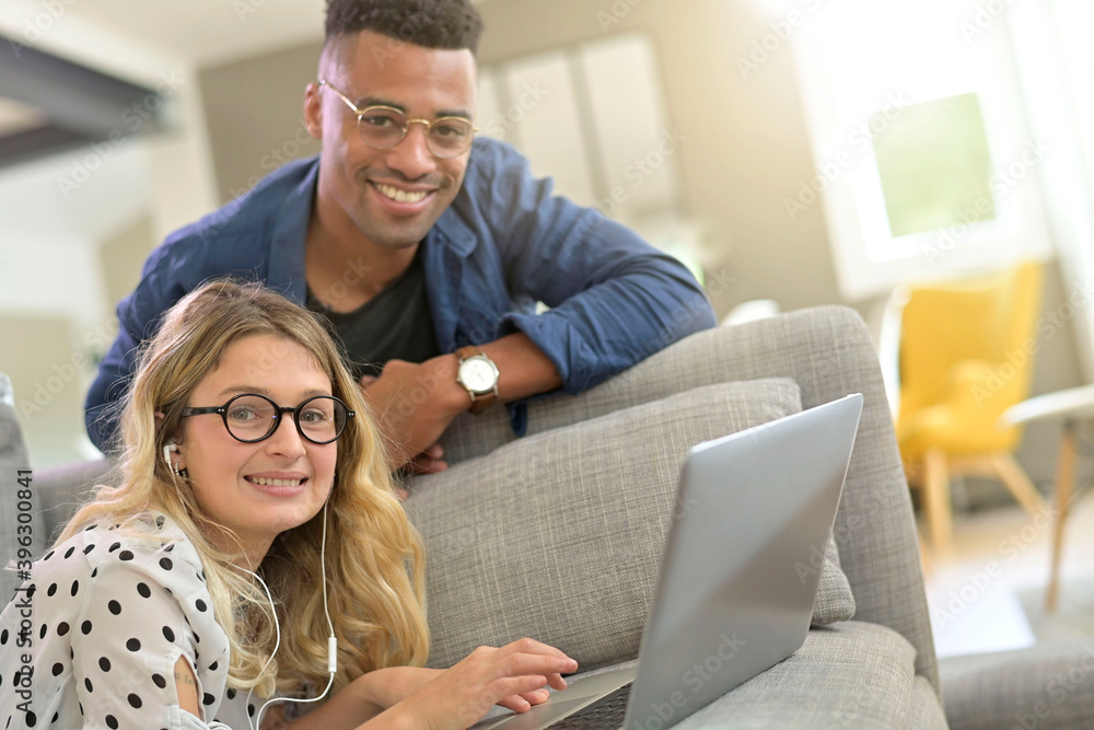Mixed-raced couple connected together on laptop at home Mixed-raced couple connected together on laptop at home