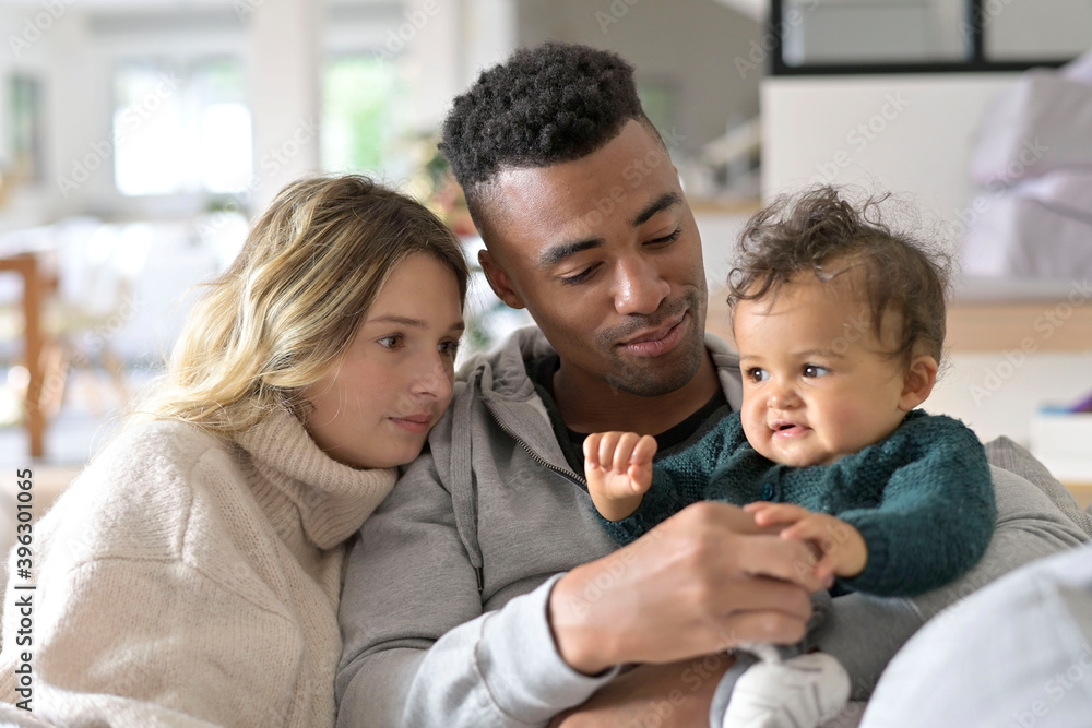 Young mixed-raced family at home cuddling baby girl Young mixed-raced family at home cuddling baby girl