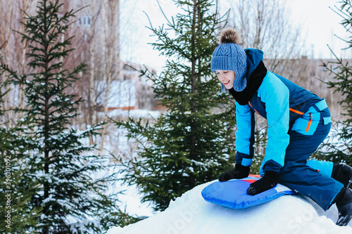 A cute teenage girl having fun on snow tube on a winter day. Wintertime, entertainment, activity, childhood, holidays concept.