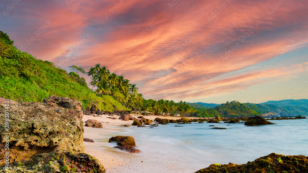 Long exposure. Beautiful and relaxing beach flanked by green palm trees at sunset. Varkala, Kerala, India.