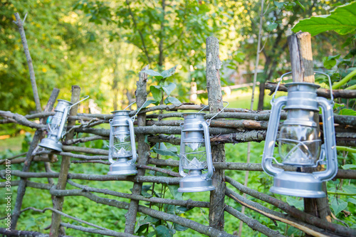 Rustic lanterns hanging on the wooden fence - street decoration and celebration concept
