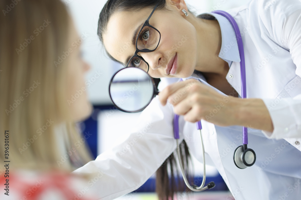 Doctor examines the patient's face through magnifying glass Doctor examines the patient's face through magnifying glass