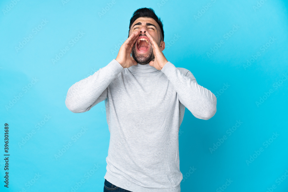 Naklejka premium Caucasian man over isolated blue background shouting and announcing something