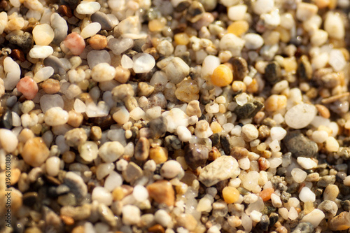 multicolored small stones on the shore on a yellow background