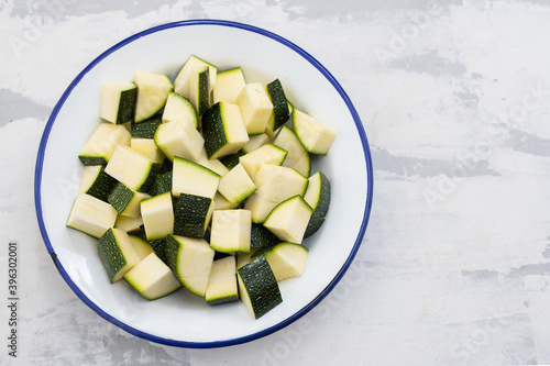 Vászonkép fresh courgette cut in cubes on white dish