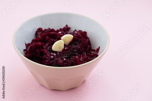 boiled beet with garlic in the bowl on pink background