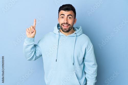 Caucasian man over isolated blue background pointing up a great idea