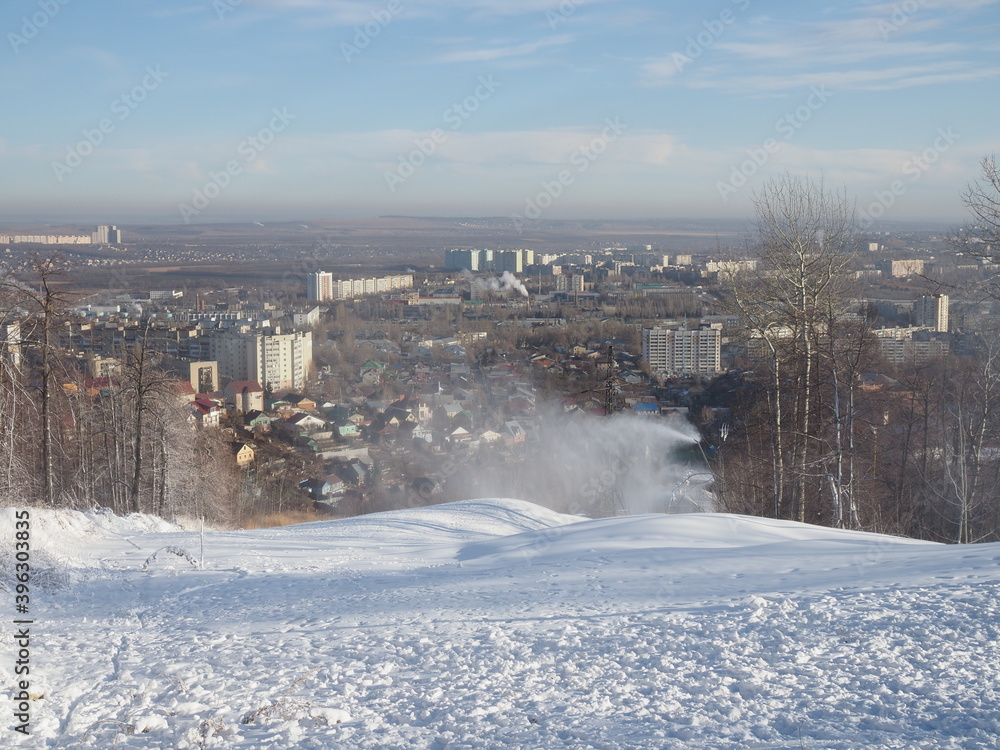 snow cannon preparing a slope to ski in the background of the urban landscape
