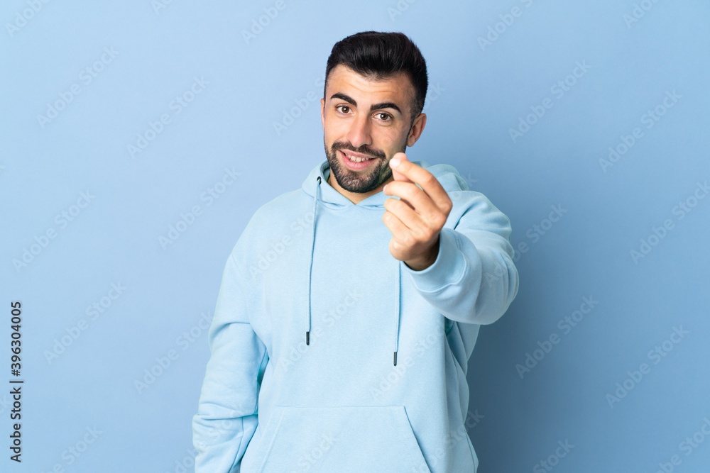 Caucasian man over isolated blue background making money gesture Caucasian man over isolated blue background making money gesture