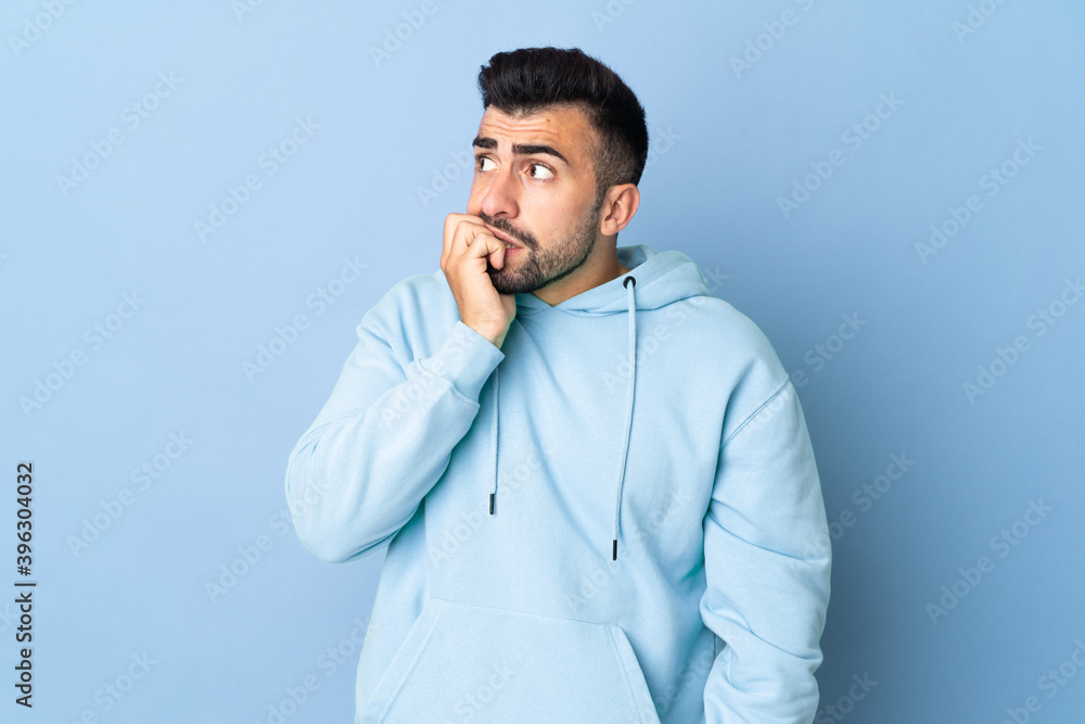 Caucasian man over isolated blue background is a little bit nervous Caucasian man over isolated blue background is a little bit nervous