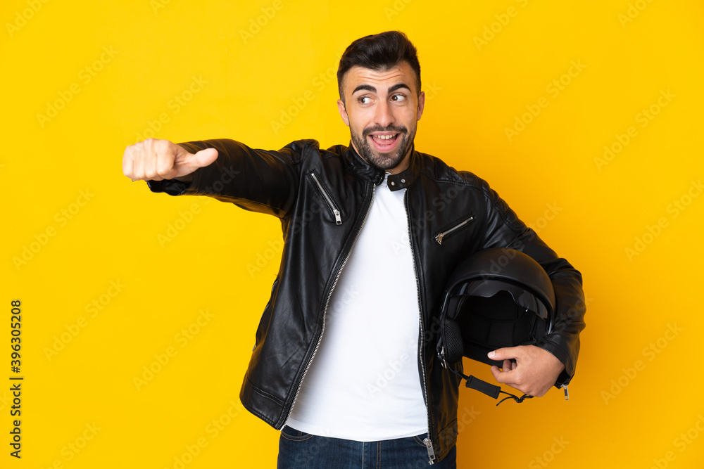 Caucasian man with a motorcycle helmet over isolated yellow background giving a thumbs up gesture Caucasian man with a motorcycle helmet over isolated yellow background giving a thumbs up gesture