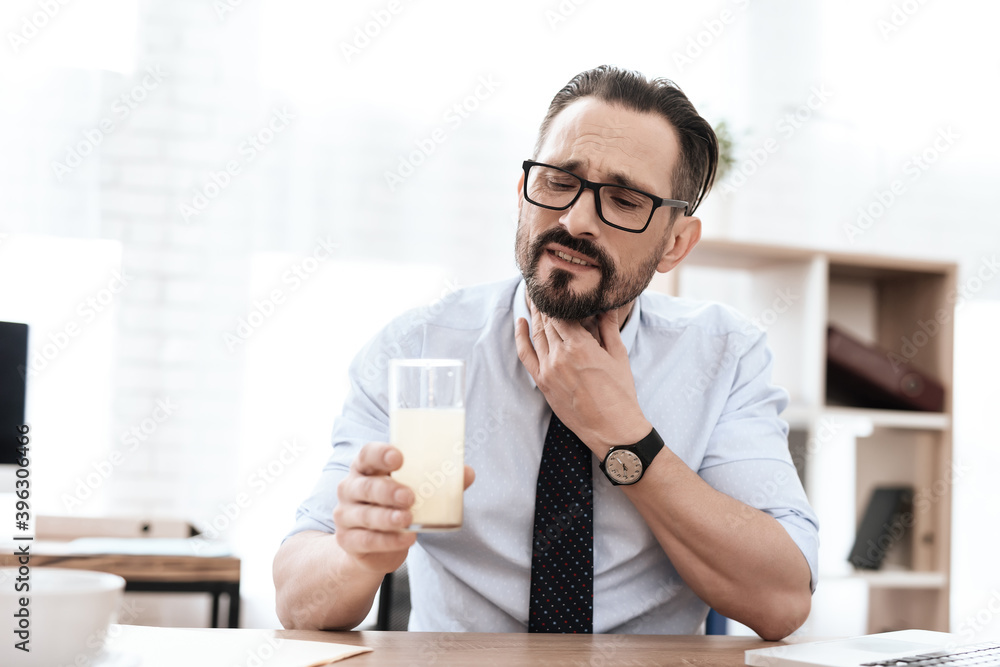 A man drinks sore throat while sitting at work. A man drinks sore throat while sitting at work.