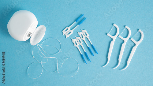 Home dental care kit. Different tools for dental care on blue background. Floss picks floss interdental brush. Top view