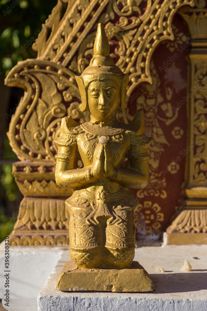 Golden ancient small statue praying warrior in temple shrine Luang Pranbang Laos