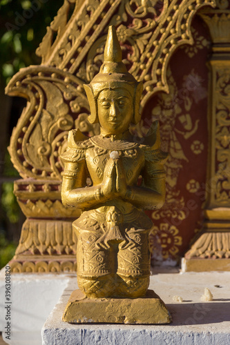 Golden ancient small statue praying warrior in temple shrine Luang Pranbang Laos