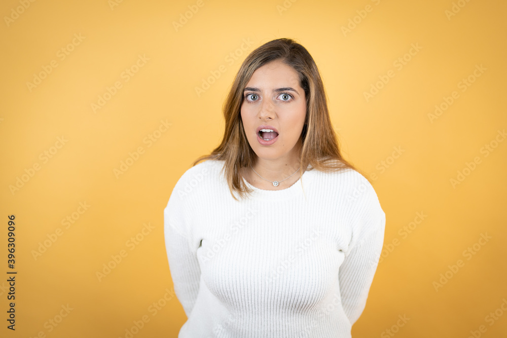 Young caucasian woman over isolated yellow background afraid and shocked with surprise and amazed expression, fear and excited face. Young caucasian woman over isolated yellow background afraid and shocked with surprise and amazed expression, fear and excited face.
