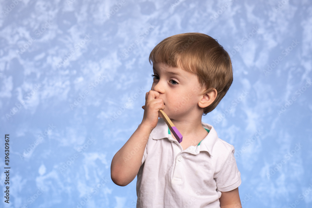 little child brushes teeth with a bamboo toothbrush in the bathroom on a blue texture background. horizontal photo. ecologicaly clean. morning hygiene concept. little child brushes teeth with a bamboo toothbrush in the bathroom on a blue texture background. horizontal photo. ecologicaly clean. morning hygiene concept.