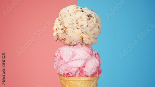 Chocolate Chip ice cream on top strawberry ice cream cone on pink and blue background.