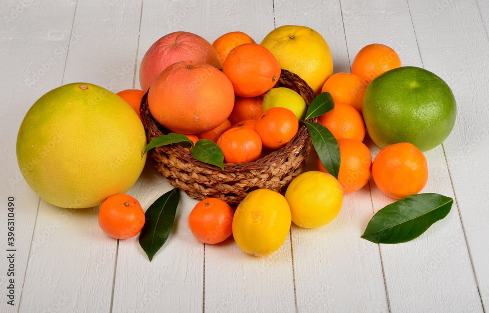 Various citrus fruits in a wicker basket on a white board Various citrus fruits in a wicker basket on a white board