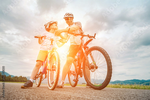 Father and son ride, cycling their bikes together, on sunny day, Happy family in helmets is riding bikes having fun.