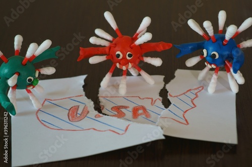 Figures of multi-colored viruses made of plasticine. Next to it is a torn map of the United States.