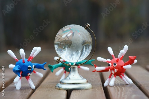 Figures of multi-colored viruses made of plasticine. Next to it is a small glass globe.