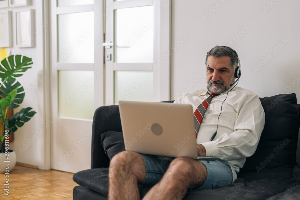man sitting on sofa and using laptop for conference call, working at home, man sitting on sofa and using laptop for conference call, working at home,
