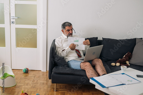 man sitting on sofa and using laptop for conference call, working at home,