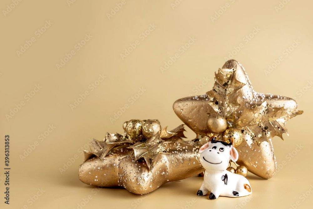 Bull symbol of the new year 2021. Ceramic small figurine of cute white bull, golden christmas fir tree and christmas decoration of star shape on pastel background. Copy space.