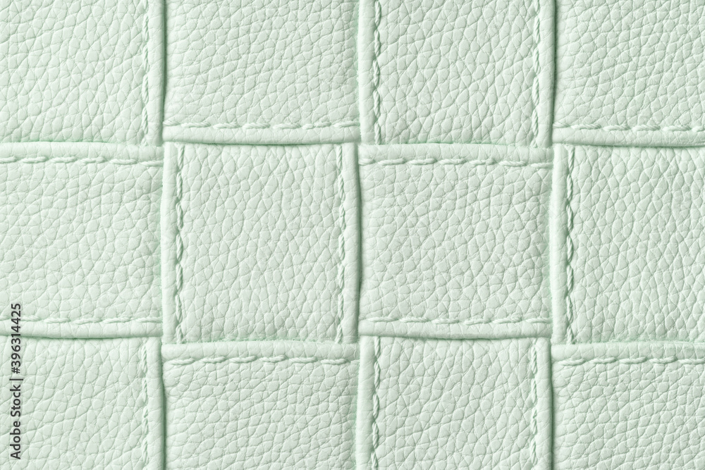 Fototapeta premium Texture of light green leather background with square pattern and stitch, macro.