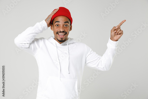 Excited young african american man 20s wearing basic casual streetwear hoodie put hand on head pointing index finger up on mock up copy space isolated on white colour background, studio portrait.