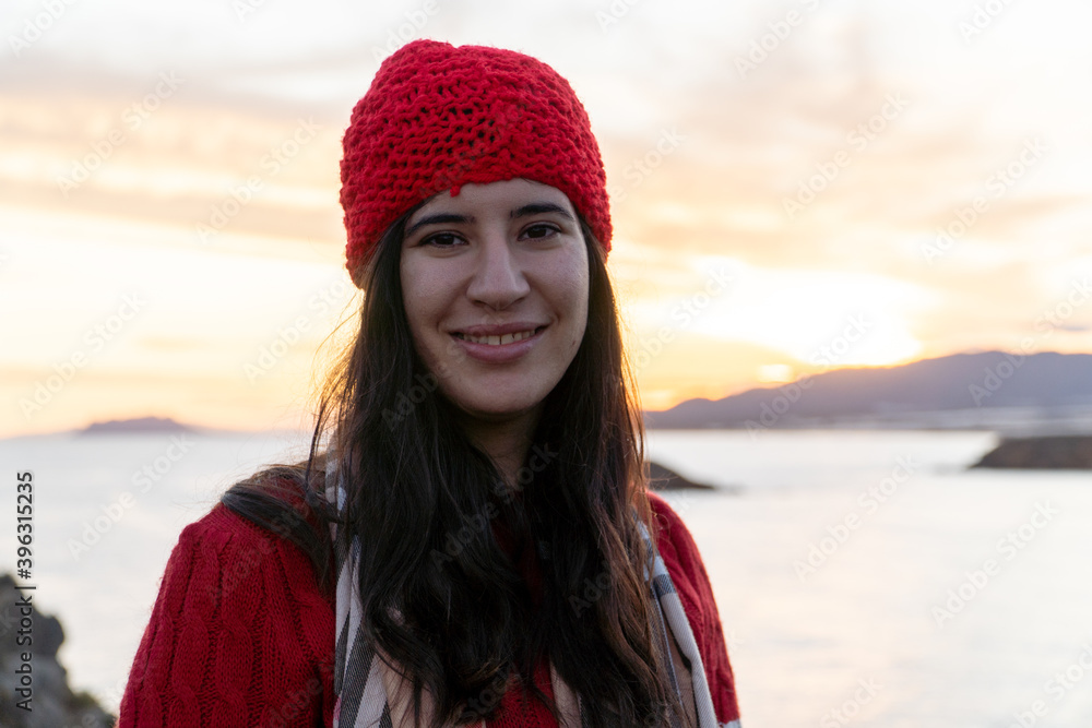 chica con gorro rojo y jersey de lana sonriendo al atardecer chica con gorro rojo y jersey de lana sonriendo al atardecer