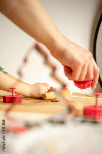 Young woman prepares gingerbread for Christmas, Pushes gingerbread shapes in dough on brown baking paper.